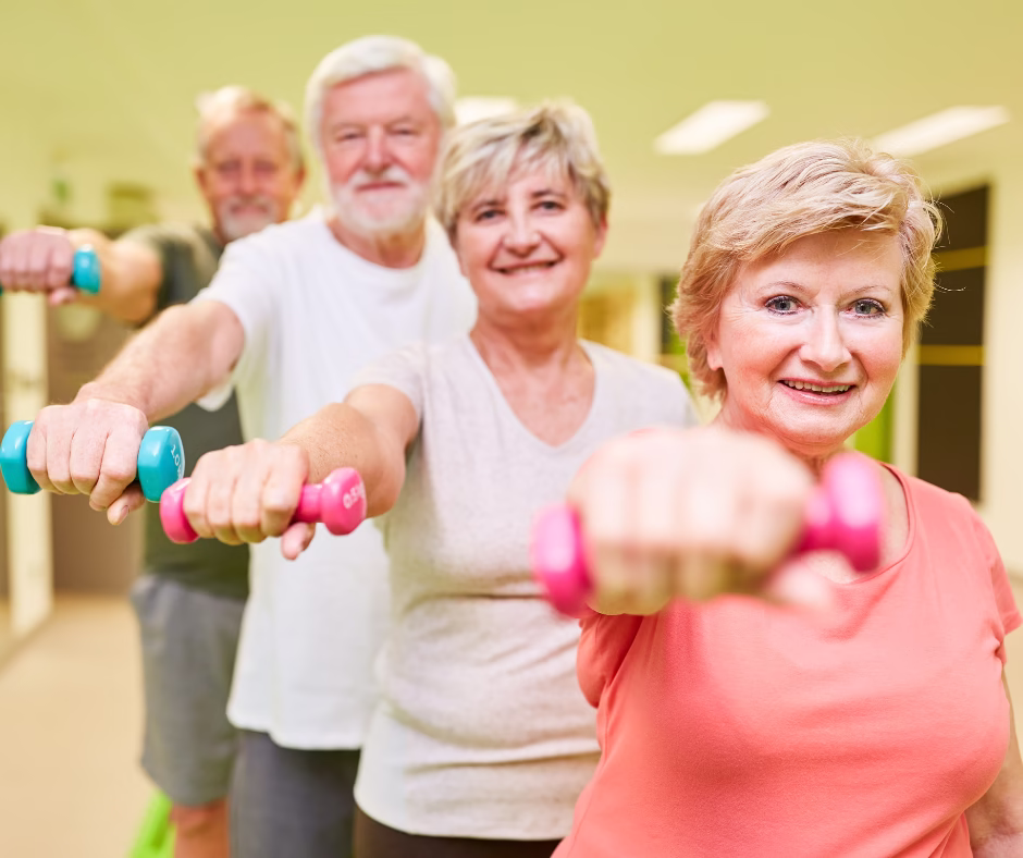 Grupo de adultos mayores sonriendo mientras hacen ejercicio con pesas en el Club Tiempo y Vida