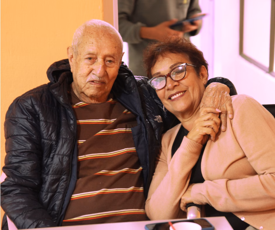 club-tiempo-y-vida-familias Un hombre mayor y su hija sonriendo juntos en el Club Tiempo y Vida, club para adultos mayores en Bogotá